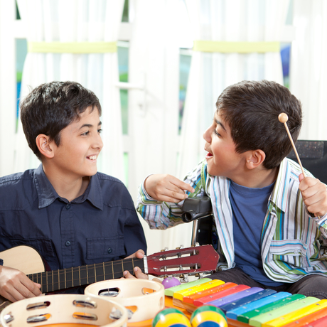 Deux garçons ayant des limitations fonctionnelles jouent d’un instrument dans un cours de musique.