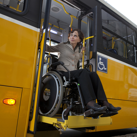 Une personne en fauteuil roulant sort d’un autobus adapté.