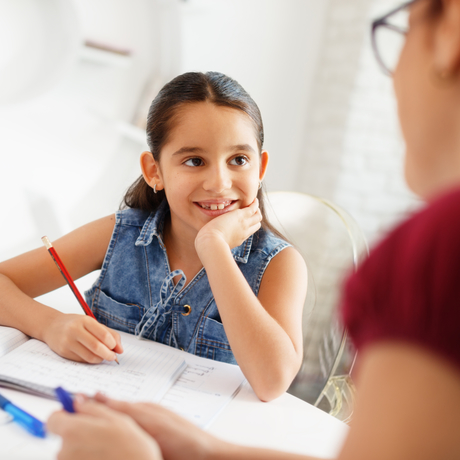 Une jeune fille fait ses devoirs accompagnée d’une adulte.