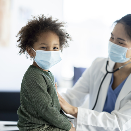 Une médecin tient son stéthoscope sur la poitrine d’un enfant.