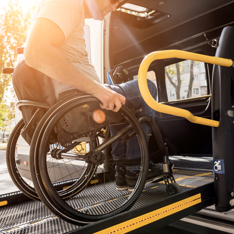 Un homme en fauteuil roulant sur l’ascenseur d’un véhicule adapté.