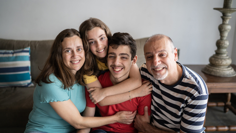 Photo d’une famille à la maison, avec leur enfant autiste.